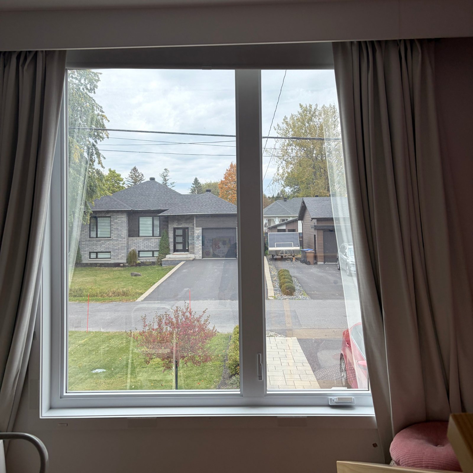 Vue de l’intérieur à travers une fenêtre traitée : la rue et les maisons voisines restent bien visibles